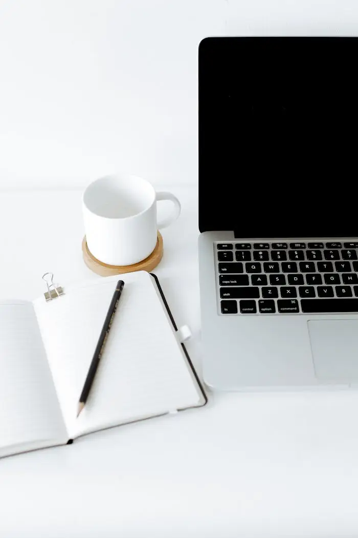 The Art of Drawing Readers In: Your attractive post title goes here High angle composition of contemporary netbook with black screen placed on white desk near opened notebook with empty sheets and white mug