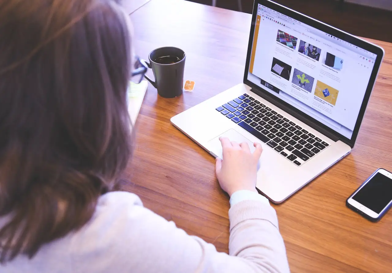 Crafting Captivating Headlines: Your awesome post title goes here Person browsing the web on a MacBook at a wooden desk with a smartphone.